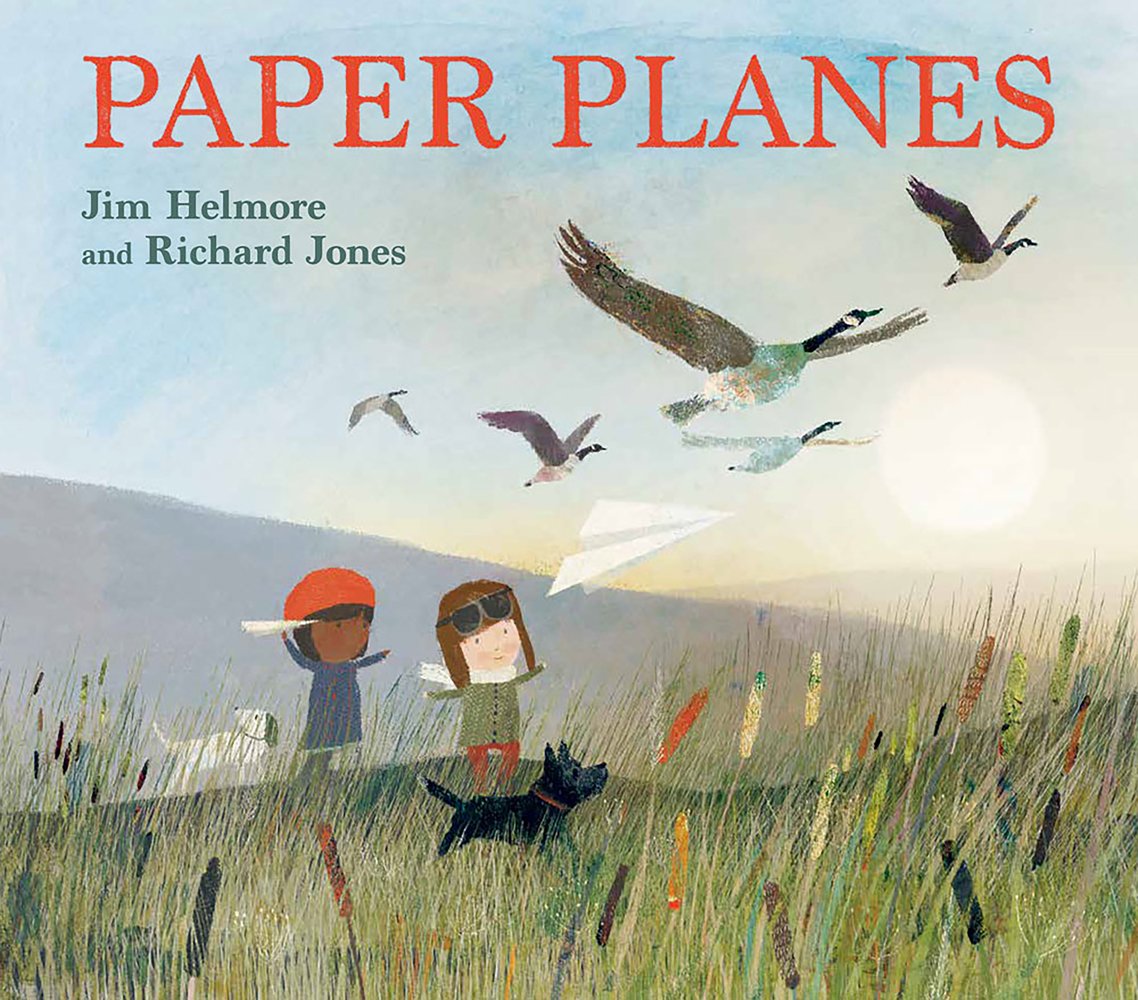 Book cover of Paper Planes by Jim Helmore, Illustrated by Richard Jones, featuring a light-skinned child and a brown-skinned child, both wearing hats and winter gear, flying paper planes in a grassy field as geese fly by.