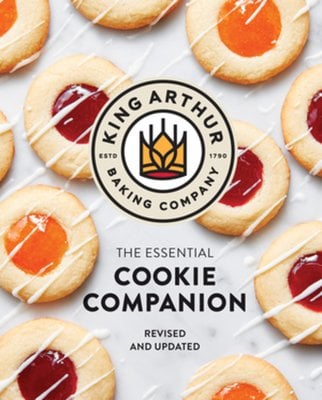 The King Arthur Baking Company Essential Cookie Companion by King Arthur Baking Company book cover featuring cookies with orange and red jam in the center with white drizzle on top.
