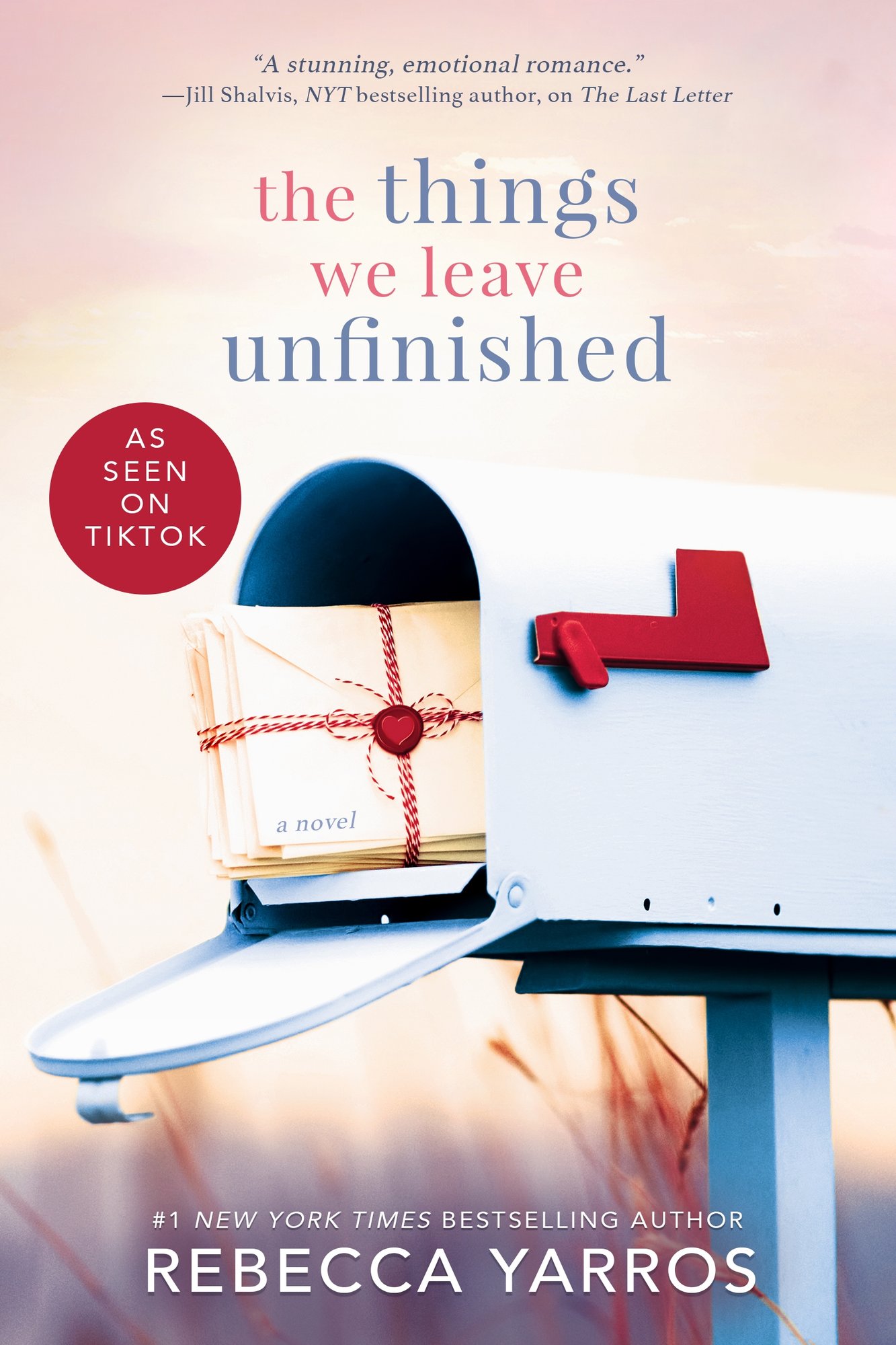 The Things We Leave Unfinished by Rebecca Yarros historical romance book cover features an open mailbox to show off a bundle of letters tied together with red and white string and a red wax seal. The background is a blurry dusk landscape and tall grass sticking up towards the mailbox. The title appears in all lowercase with alternating blue and red text. The author's name is in all white caps at the very bottom.