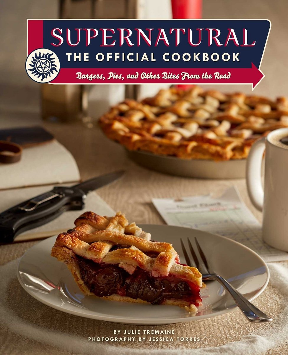 Supernatural: The Official Cookbook by Julie Tremaine book cover. A piece of pie sits on a white plate on a set table.