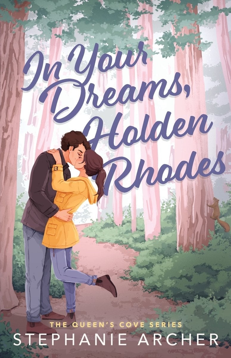 In Your Dreams, Holden Rhodes by Stephanie Archer, book cover. The title "In Your Dreams, Holden Rhodes," is written in blue. The background is trees on a tails. There is a woman kissing a man and she is wearing a yellow rain coat. Her foot is popped up.