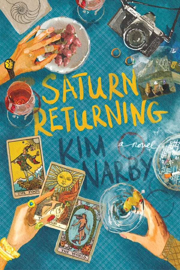 Saturn Returning by Kim Narby, a fiction book cover depicting art of three hands reaching onto a blue tablecloth littered with tarot cards, drink glasses, a camera, a photograph, and an ashtray.