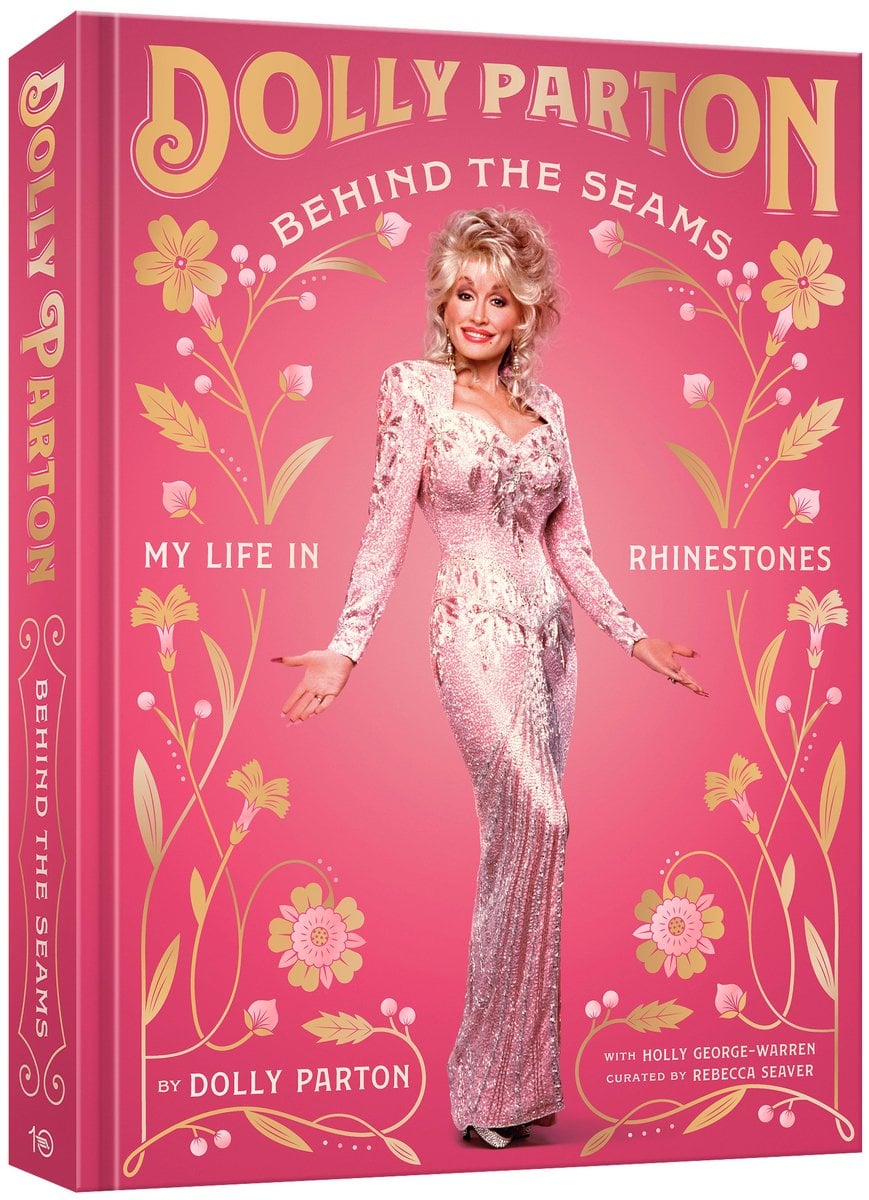 Dolly Parton's "Dolly Parton: Behind the Scenes" is a soft pink cover with pale yellow flowers with Dolly Parton standing in the center wearing a long, pink dress and her hair pulled up in a formal fashion.