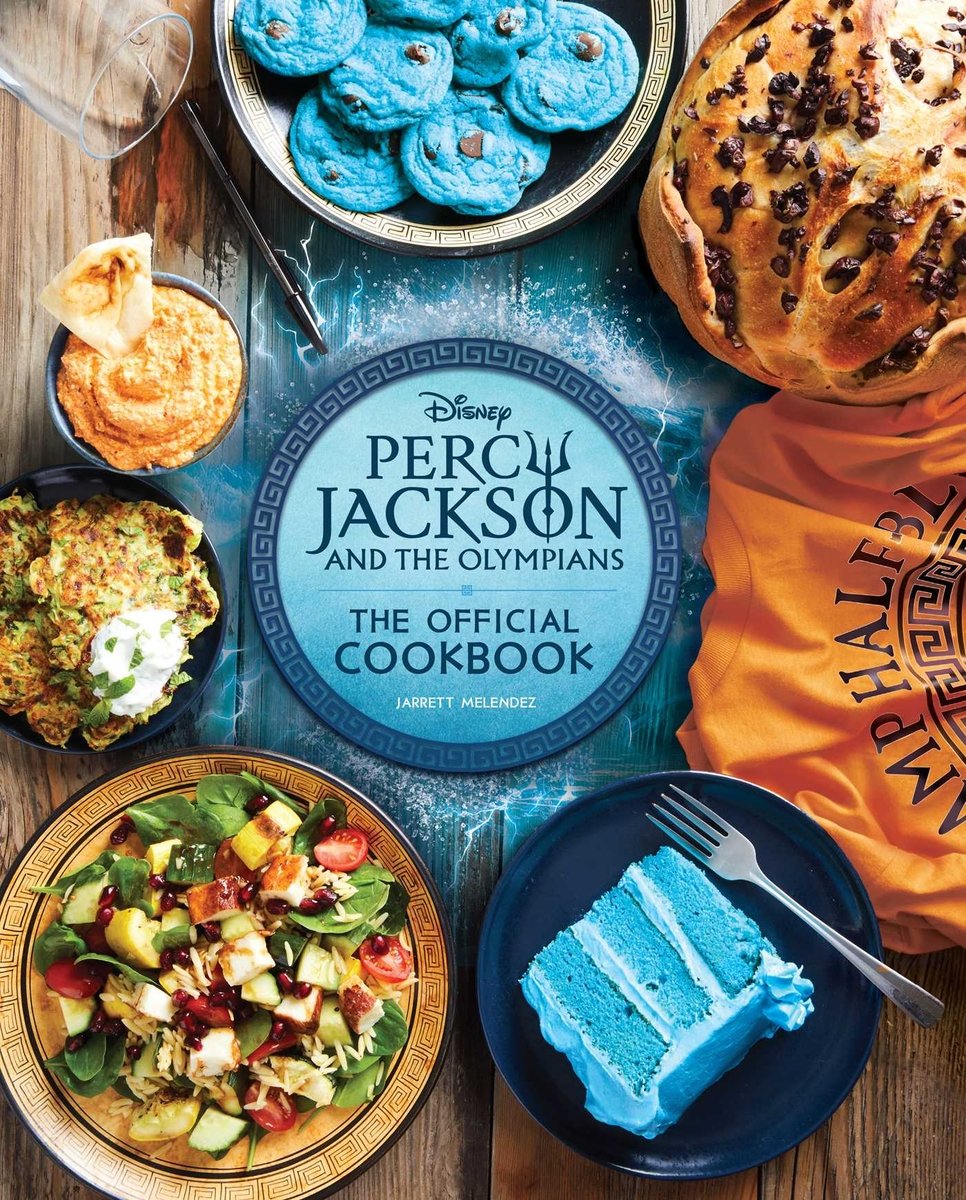 Percy Jackson and the Olympians: The Official Cookbook by Jarrett Melendez book cover. Hummus, a salad, and two blue desserts are pictured above and below the title.