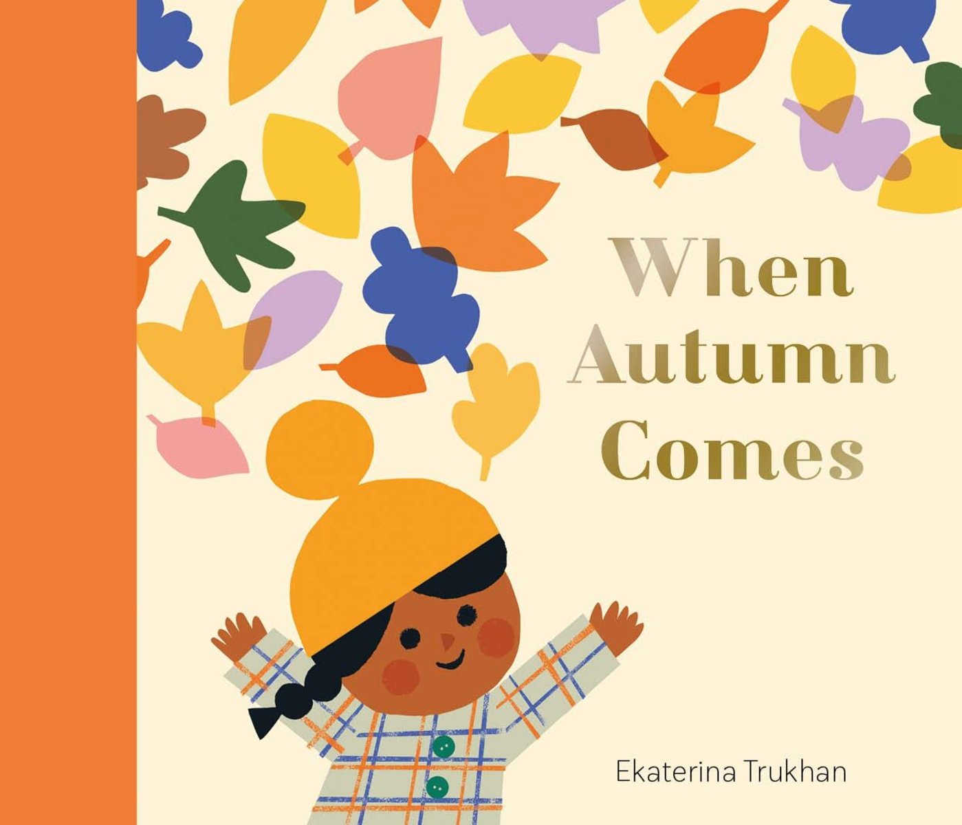 Book cover of When Autumn Comes by Ekaterina Trukhan, featuring a brown-skinned child with long, dark braided hair wearing a yellow knit cap and plaid coat holding their hands up as colorful autumn leaves rain down.