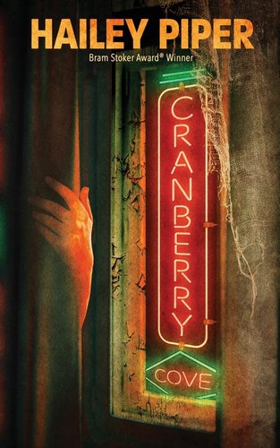 Cranberry Cove by Hailey Piper book cover with a neon sign, spiderwebs, and a mysterious hand.